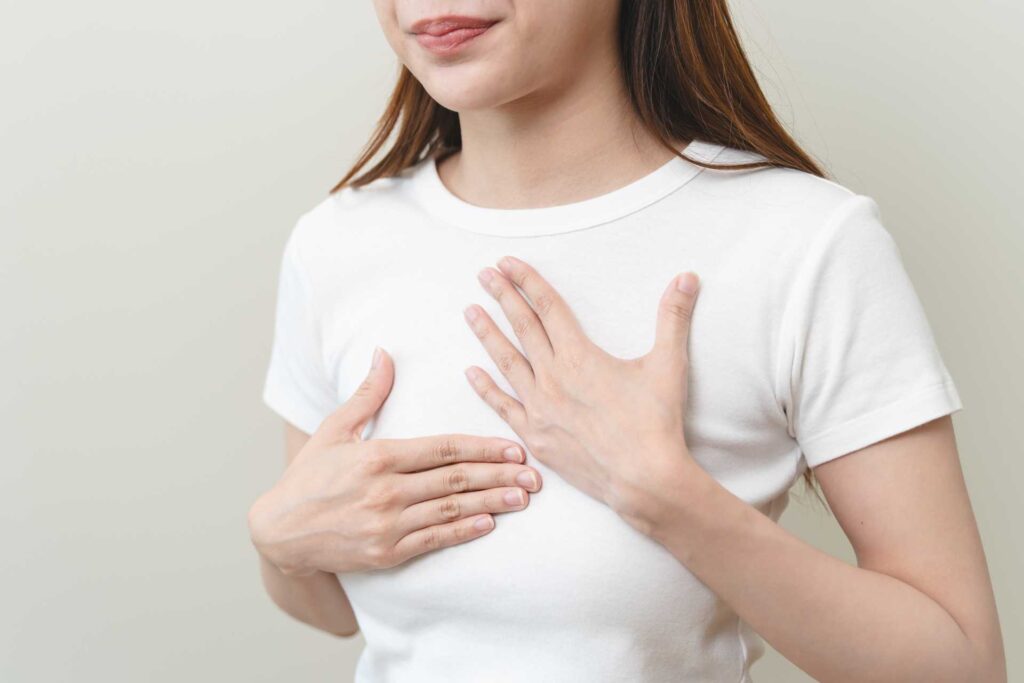 Donna che si tocca il petto in corrispondenza dell'esofago per l'acidità e reflusso.