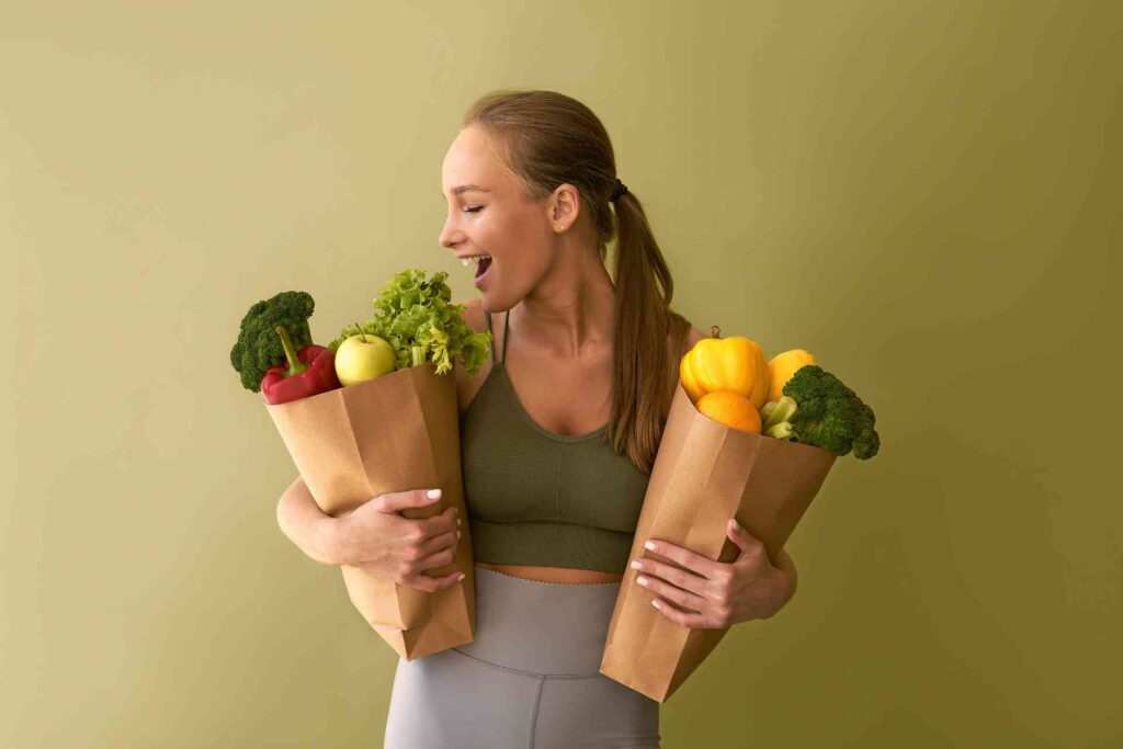 Donna felice con le buste della spesa piene di verdure e frutta