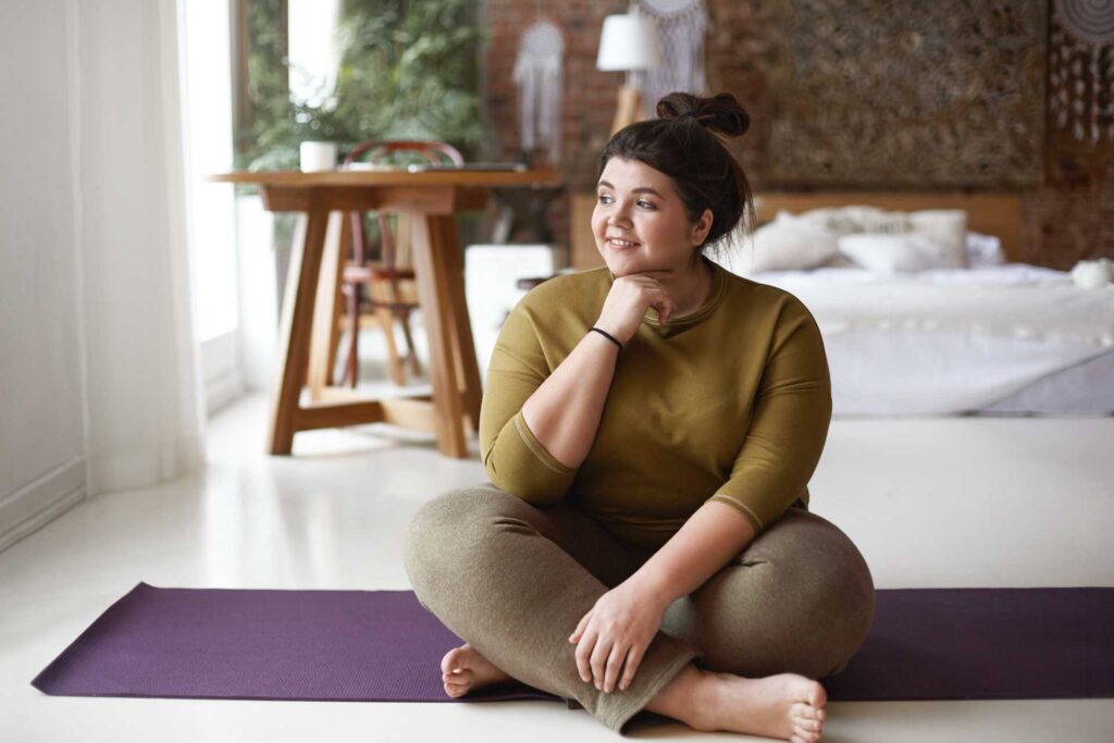 ragazza in sovrappeso su un tappetino di yoga che cerca di dimagrire