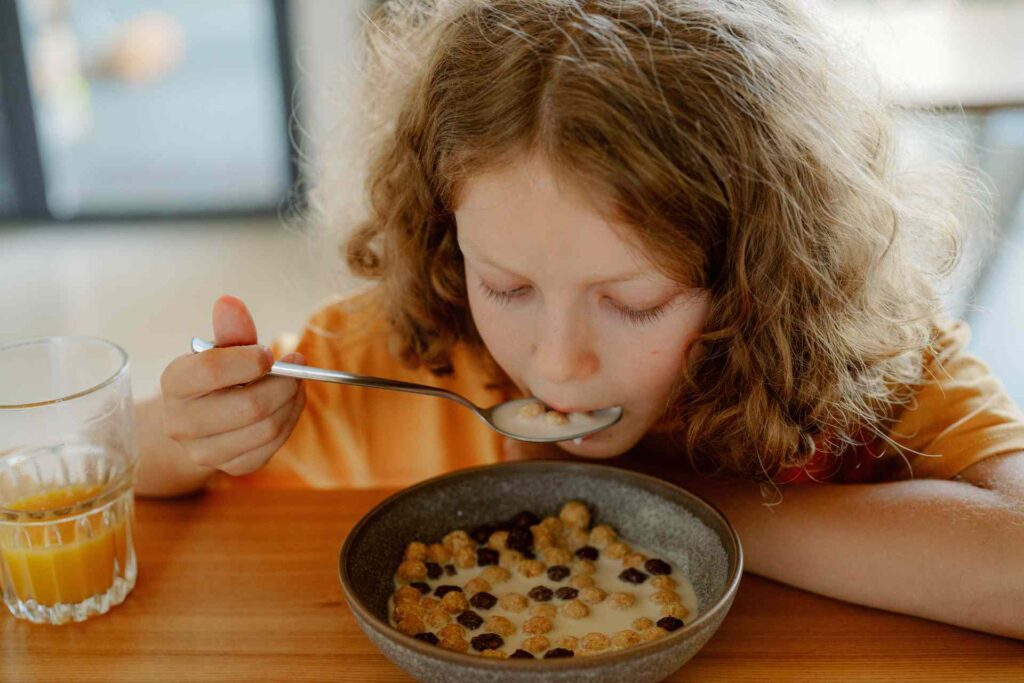 Bambino a tavola che mangia latte e cereali