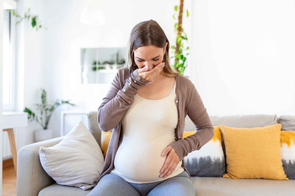Donna in gravidanza che soffre di nausea sul divano