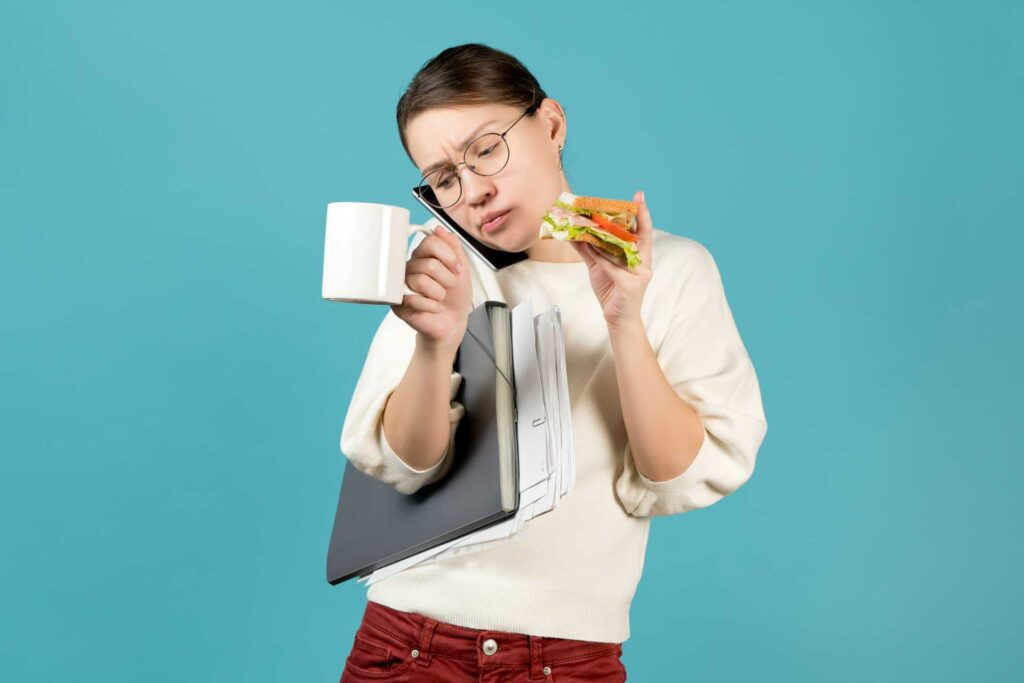 ragazza stressata dal lavoro mangia un panino al volo