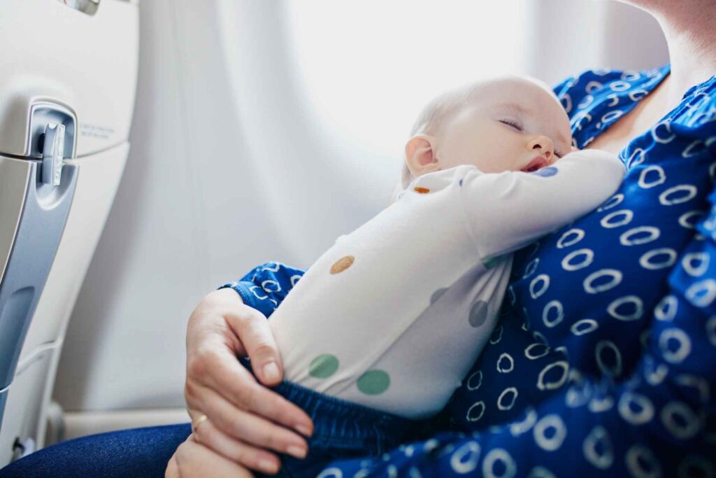 neonato dorme sulle braccia della mamma in aereo