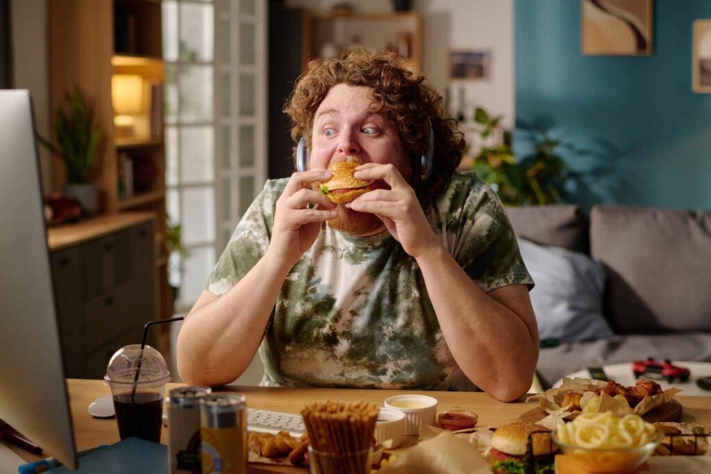 ragazzo mangia junk food guardando il pc