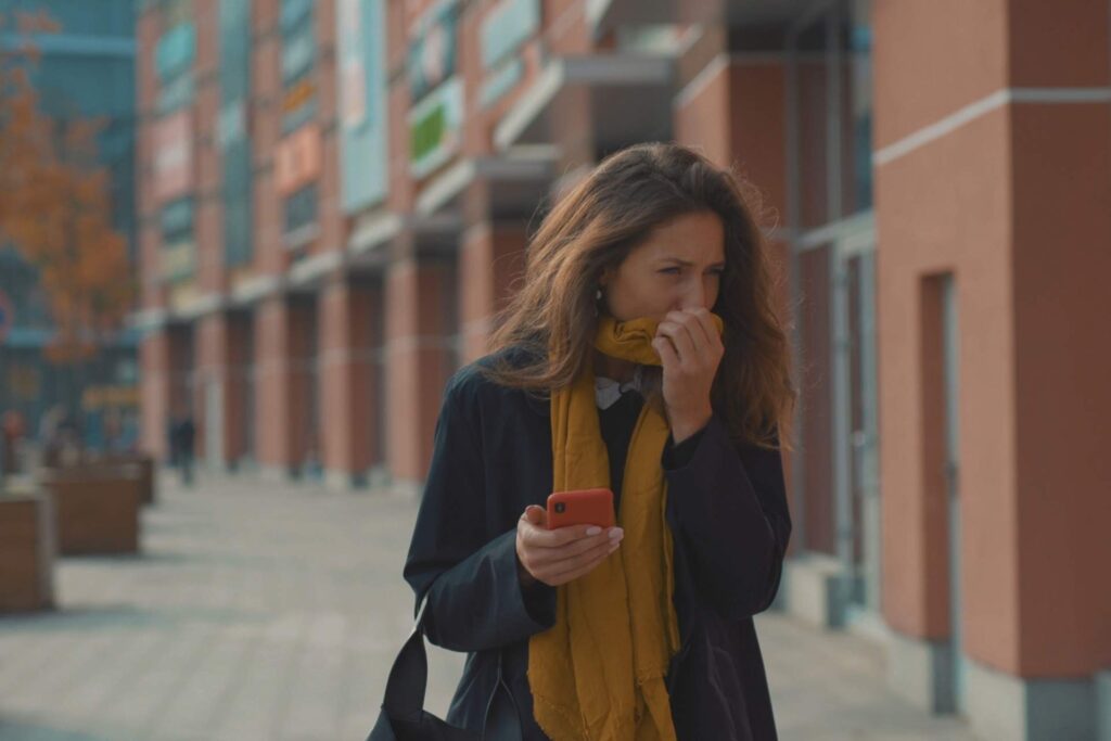 donna cammina per strada coprendosi il naso con la sciarpa per l'aria pesante